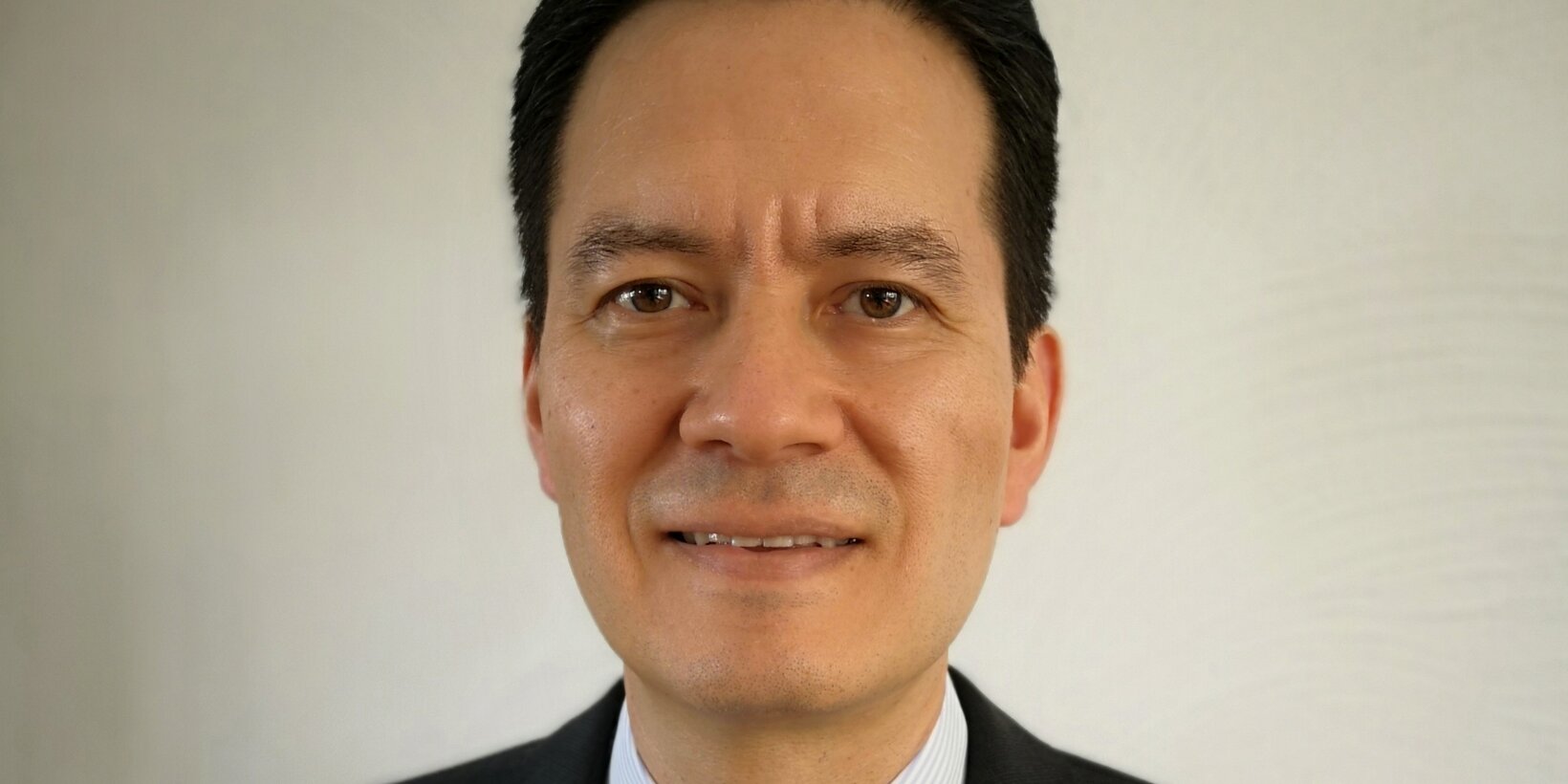 Portraitbild einer männlichen Person im Anzug vor weißem Hintergrund