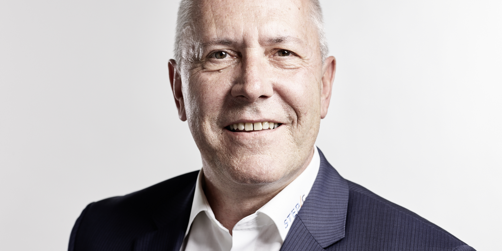 Portraitbild einer männlichen Person im blauen Nadelstreifenanzug vor weißem Hintergrund