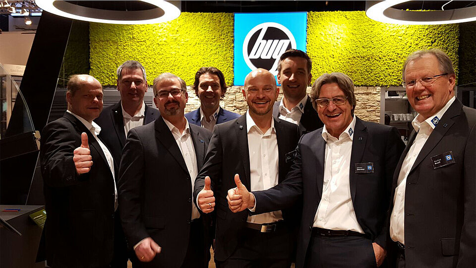 Eight people from BUG stand in front of the BUG booth at BAU 2017