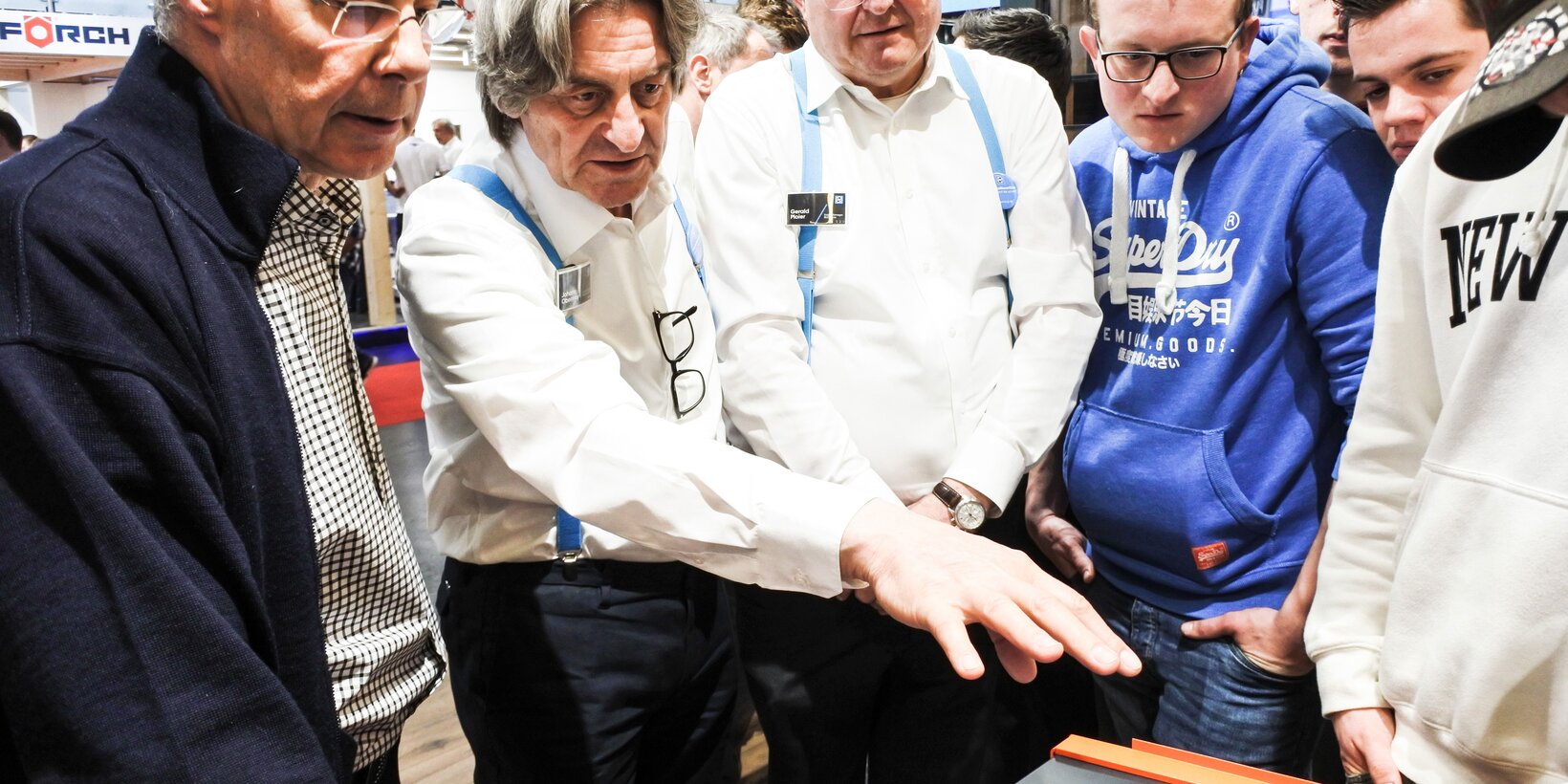 Two BUG employees present the window sill solution to six visitors at the booth