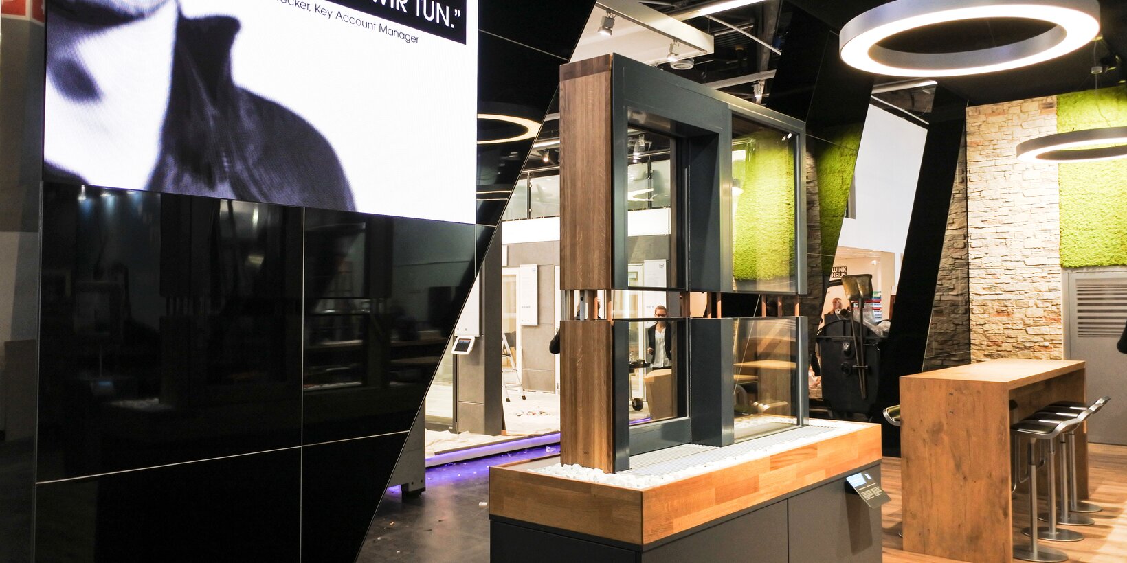Section of the exhibition booth with a window sample and a high table with chairs