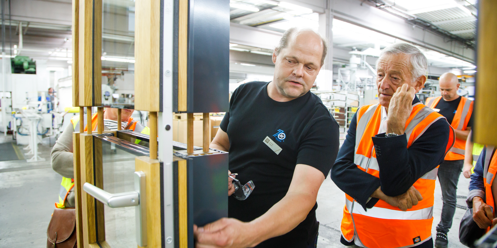 Two people stand at a window exhibit made of wood and aluminium from BUG