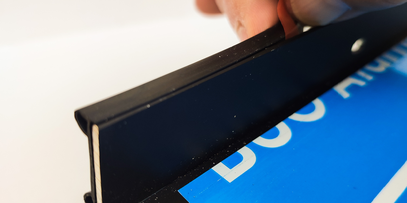 Positionierung der schwarzen Anschraubdichtung AD 500 am Anschraubsteg einer schwarzen Fensterbank