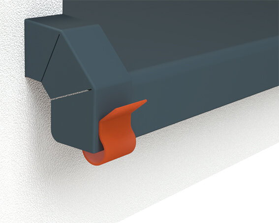 Aufgesteckte orangene Sicherungsklammer auf dem Gleitabschluss A 500 V mit grauer Fensterbank