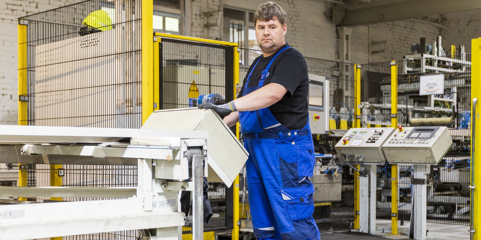 Mitarbeiter steht an einer Maschine für das Folieren von Fensterbänken